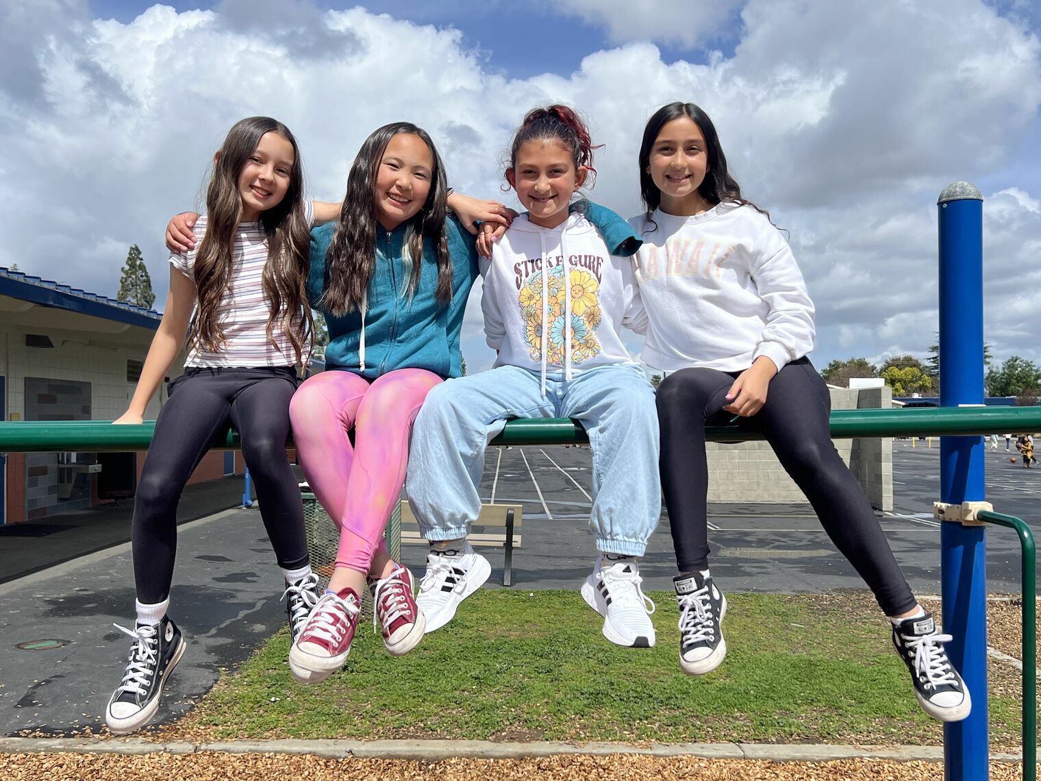 4 students sit on monkey bars