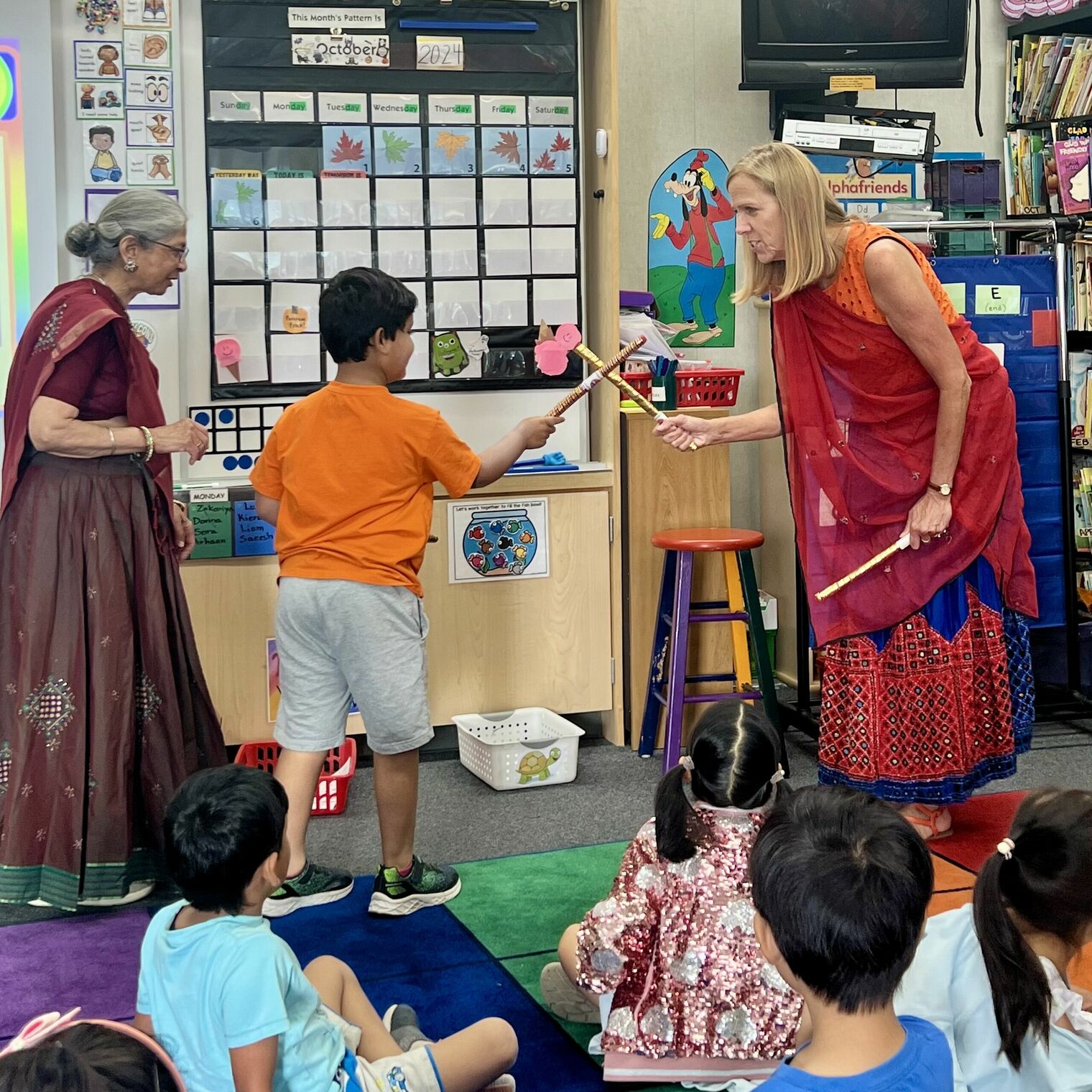 Student and principal learning Raas with sticks.