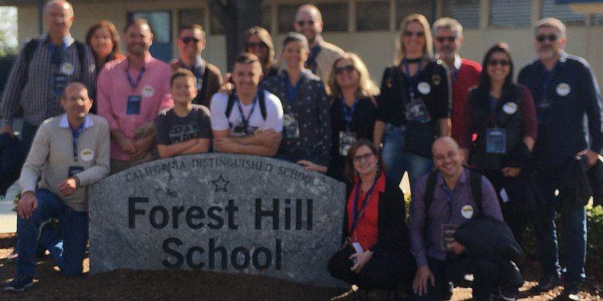 people standing in front of the Forest Hill School sign