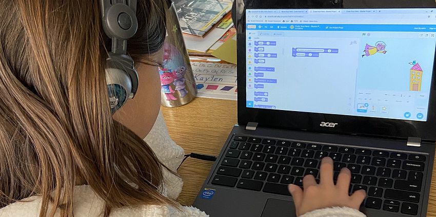 student coding on a computer with headphones on