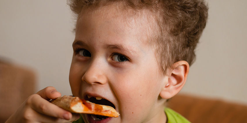 boy biting a pizza slice