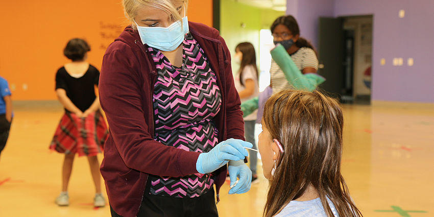 health worker swabs a student's mouth as part of the COVID-19 testing