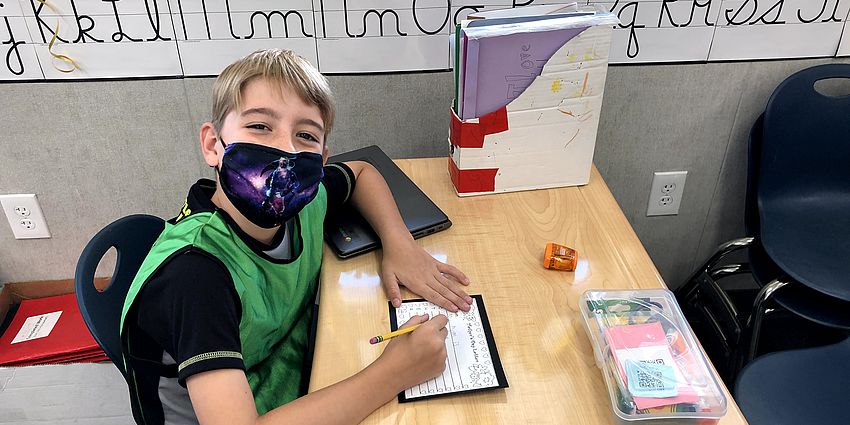 boy student smiling behind mask