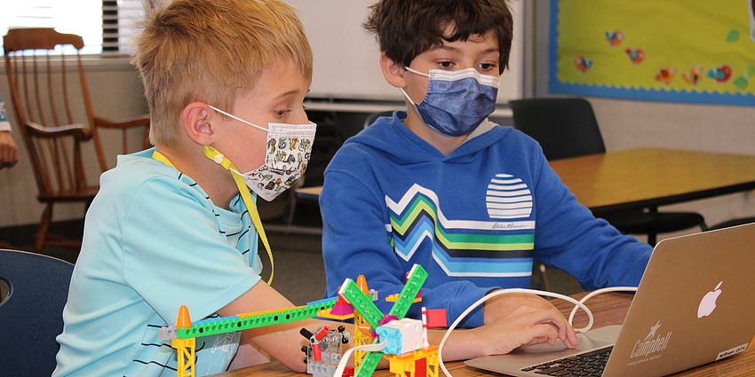 two boys work together on lego project