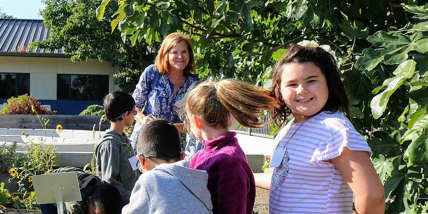 school girls smiling in garden with other students and adult volunteer