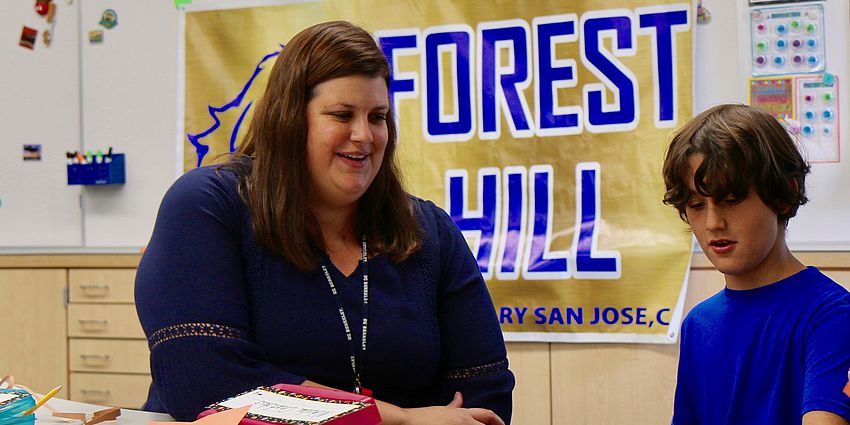 teacher with student. sign behind says forest hill