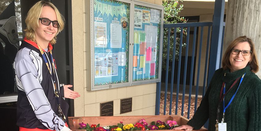 student and principal standing in front of a planter box