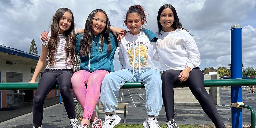 4 students sit on monkey bars