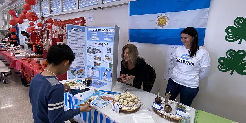 child standing in front of a table with food from a different country