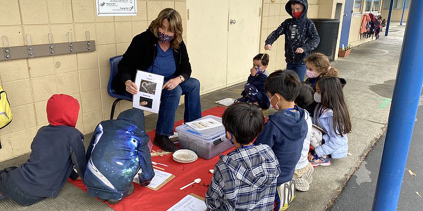 Teacher teaching a lesson to a small group of students outside