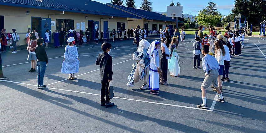 students in costumes stand in rows on playground
