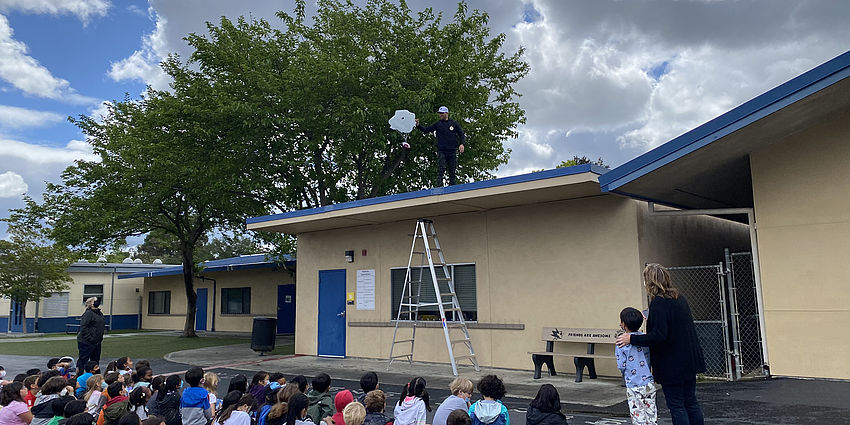 Group of students gathered outdoors watching the egg drop