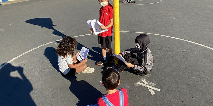 STudents sitting outside reading from their poetry packet