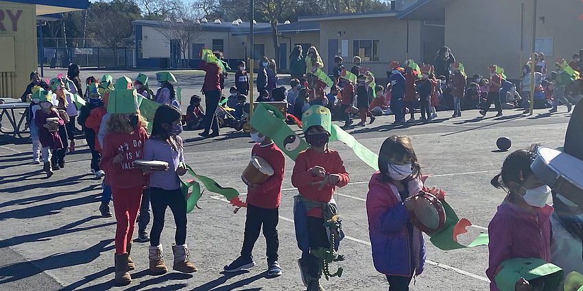 Students marching in a parade with dragon headpieces.
