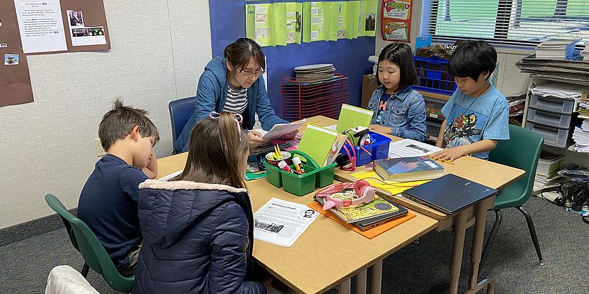 children working at their desks with a parent helping them