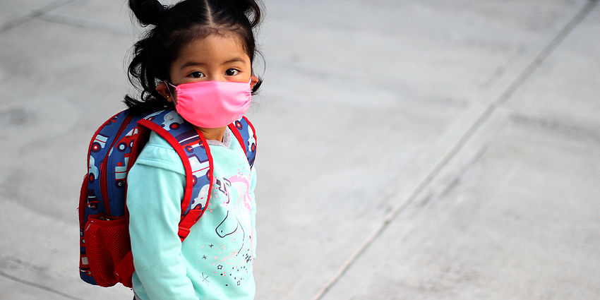 Little girl with backpack wearing a facial mask.