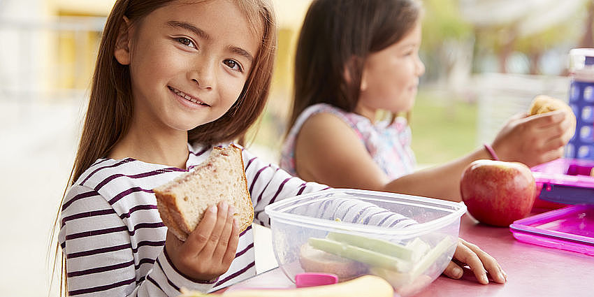 A little girl eating her sandwich at school