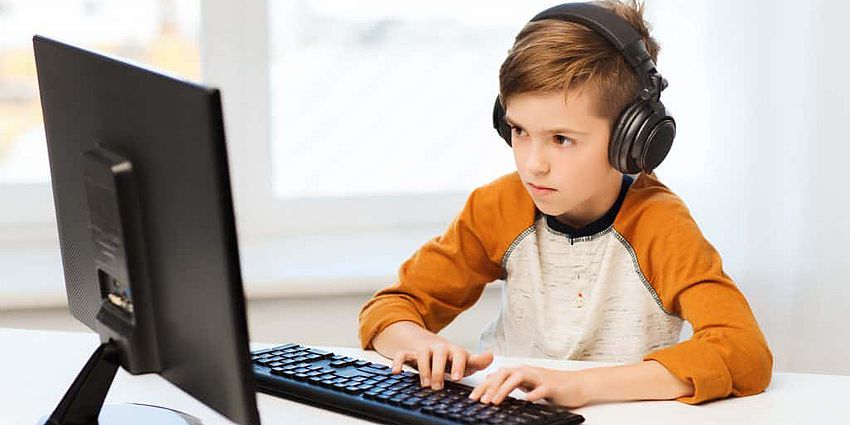 boy sitting at a computer with headphones on