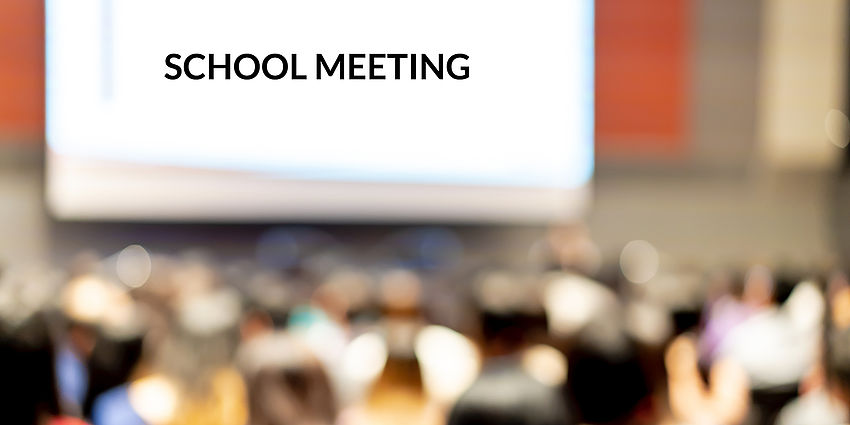 a meeting with a screen down that says "school meeting"