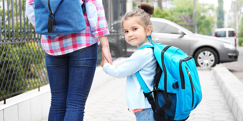 little girl looking at camera and holding mother's hand