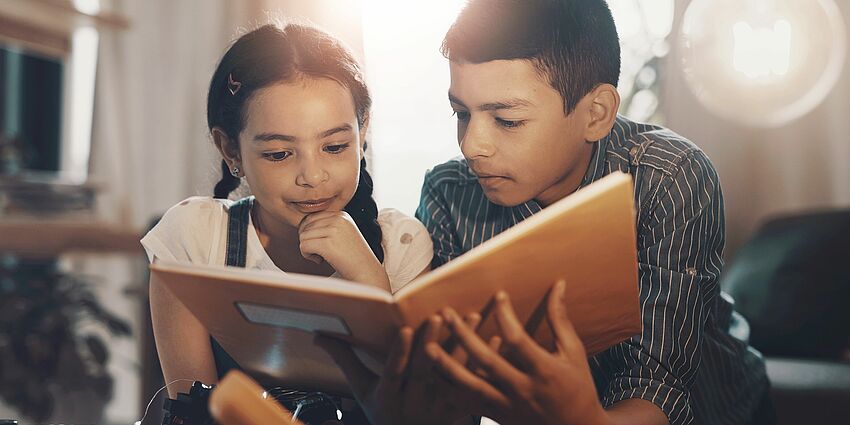 brother and sister reading together at home