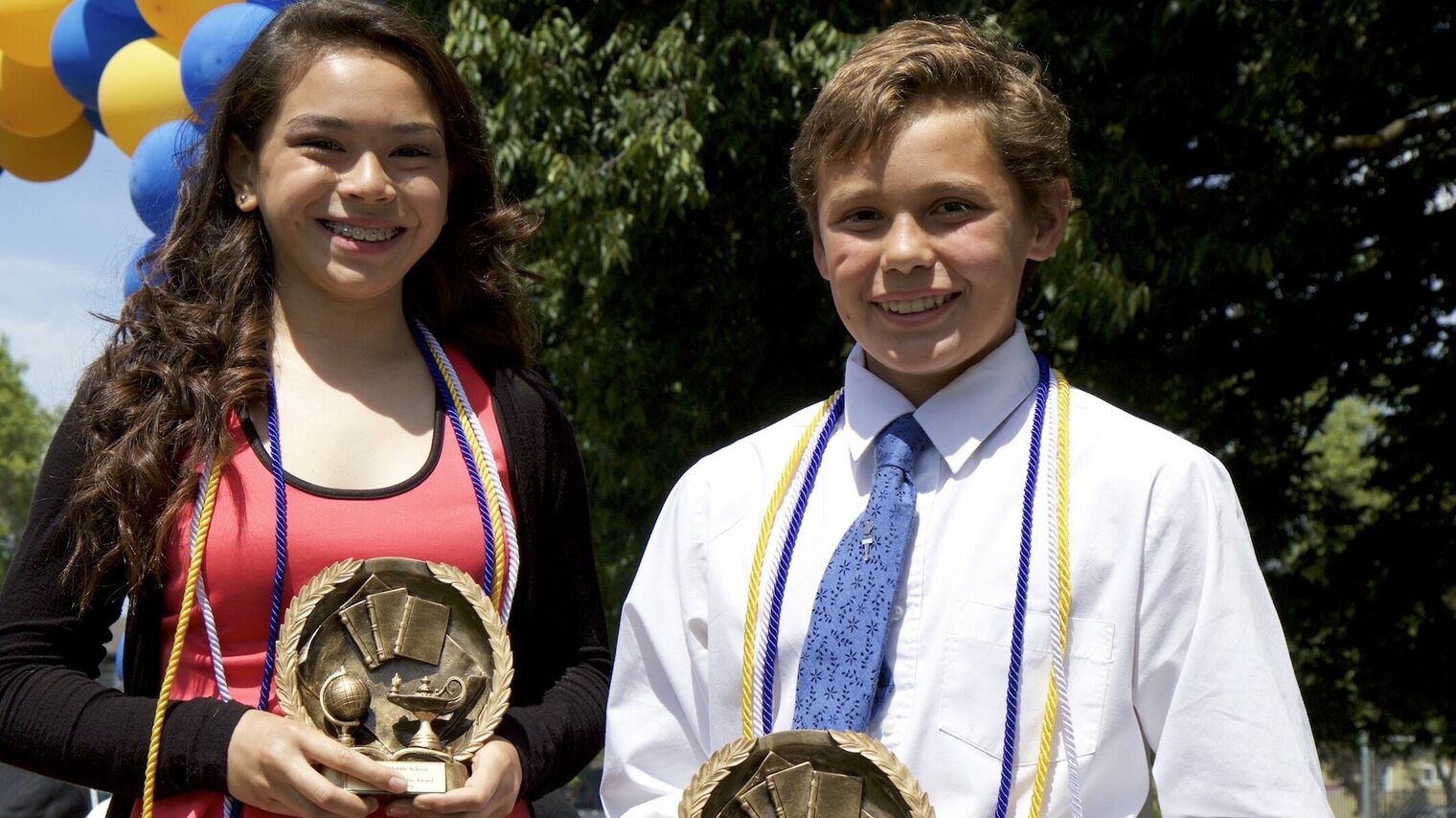 students holding academic award trophies