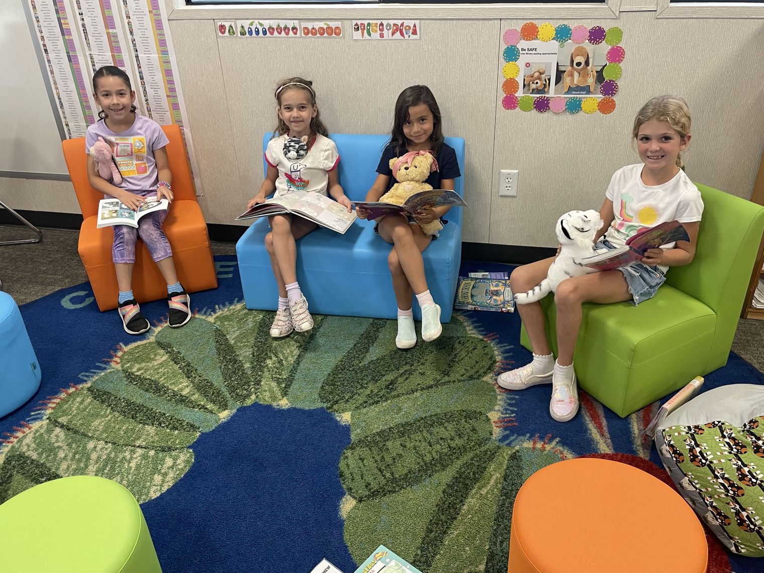 Students and teddy bears read in the library