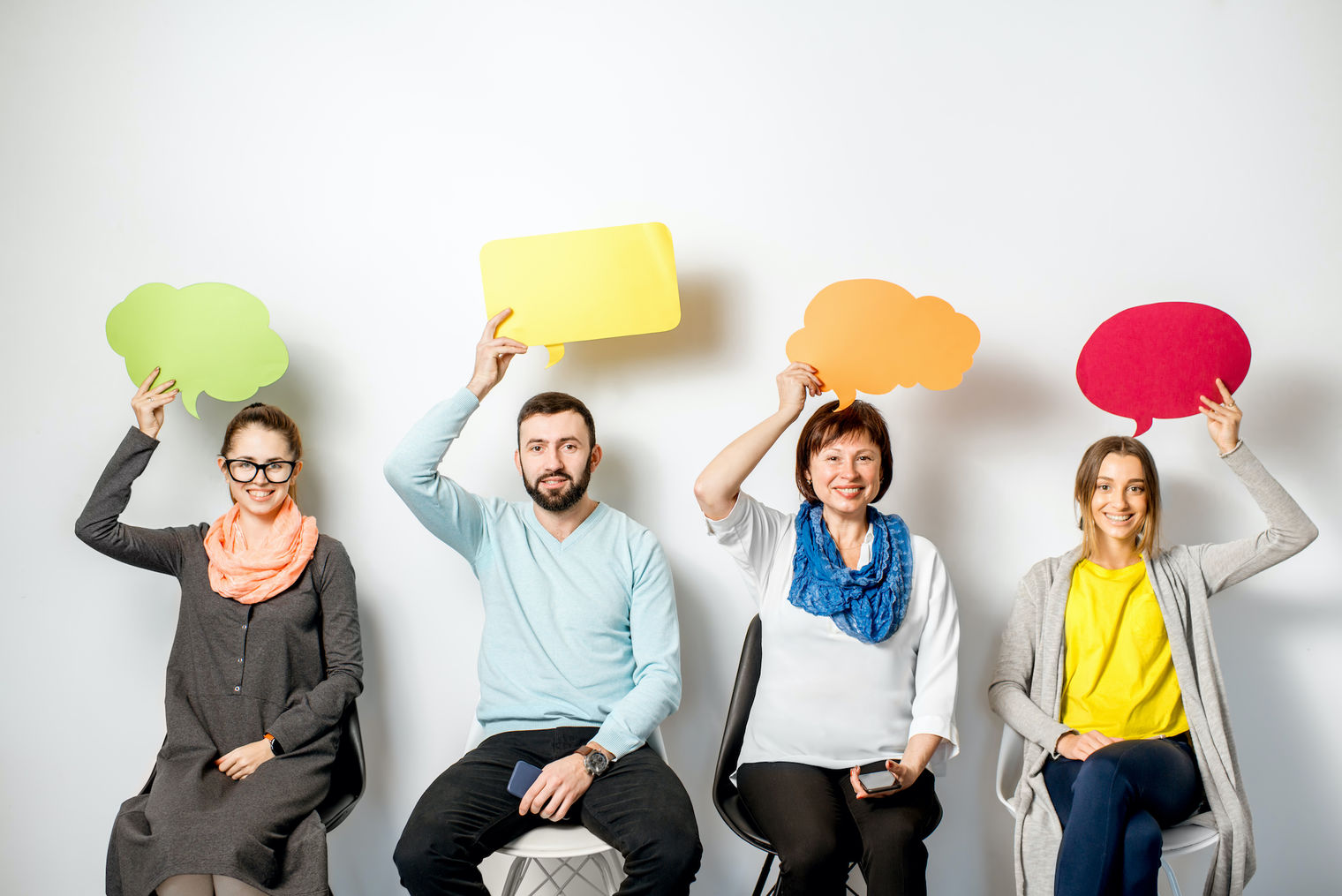 men and women holding thought bubbles over head